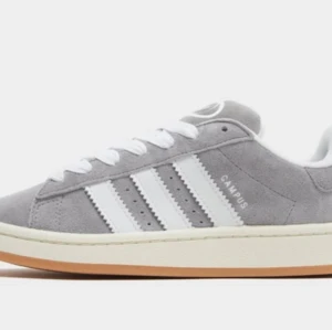 Grå Adidas Campus sneakers mocka - Snygga Adidas Campus sneakers i grå mocka med klassiska vita ränder på sidorna och vit sula. Skorna har snörning och en låg profil som ger en clean och tidlös look. Perfekta för dig som gillar streetstyle och vill ha något som funkar till det mesta. Storlek 41, använt 1 gång men passar inte mig därav säljs dem. Kan skicka eller mötas up i Malmö. Köpt för 900 kr på deichman. Säljer för 650 kr då dem är i nyskick. 