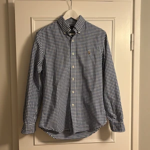 Rutig blåvit skjorta från Ralph Lauren - Snygg rutig skjorta från Ralph Lauren i blått och vitt. Slim fit-modell med klassisk krage, knappar hela vägen och broderad logga på bröstet. 