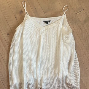 Vit linnetopp från Massimo Dutti XS - Superfin vit linnetopp från Massimo Dutti i storlek XS. Toppen har tunna axelband, v-ringning och ett plisserat tyg med diskreta prickar för en extra cool textur. Lätt och luftig med innerfoder, perfekt för varma dagar eller lager på lager.