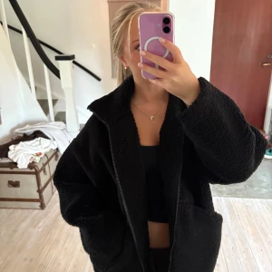 Svart teddyjacka med dragkedja - Mysig svart teddyjacka med oversized passform och stora fickor. 