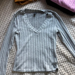 Grå ribbad v-ringad tröja Shein  - Grå långärmad tröja från Shein med v-ringning och ribbat mönster. Tröjan är i mjukt material och har en slim passform som sitter snyggt på kroppen. Pris går att diskutera.
