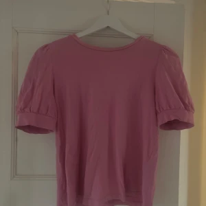 Rosa topp med puffärm från Vero Moda - Säljer en söt rosa topp från Vero Moda. Toppen har puffiga söta korta ärmar och rund halsringning. Tillverkad i mjuk bomull🩷