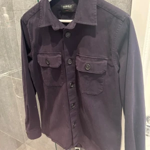 Mörkblå overshirt från Gabba - Säljer nu denna extremt populära overshirt eftersom jag fick en ny precis. Denna overshirt kan man verkligen ha på sig överallt eftersom den passar verkligen till allt. Det är inga skador eller nåt sånt. Storleken är S men passar även folk i storlek medium 