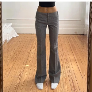 Grå kostymbyxor med bootcut - Snygga grå kostymbyxor med låg midja och bootcut-silhuett från Topshop. Bilden är från föregående ägare. Köpta här på Plick, men alldeles för stora i midjan på mig. Midja 39, innerben 81. De är sååå fina 💕💕
