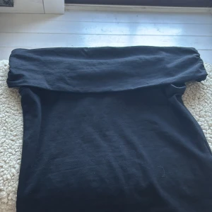 Svart offshoulder klänning - Säljer en svart  offshoulder-modell och ärmlös design. I mjukt bomullstyg och har en enkel, stilren look som passar perfekt till sneakers eller boots. Snygg och bekväm för dig som gillar minimalistisk stil.