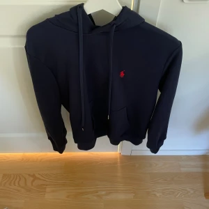 Mörkblå hoodie från Polo Ralph Lauren - Säljer nu min snygga mörkblå hoodie från Polo Ralph Lauren med klassisk röd broderad logga på bröstet. Tröjan har används några få gånger men har inga tecken på användning.