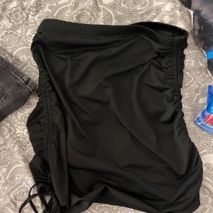 Svart kortkjol med snörning i sidorna - Snygg svart kortkjol med tight passform och cool snörning i båda sidorna. 