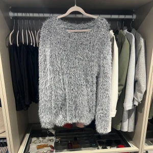 Gråsvart fluffig stickad tröja - Supermjuk och fluffig grå stickad tröja med lång ärm och rund hals. Perfekt för dig som vill ha en cozy look. Tröjan har en oversized känsla och är lätt att matcha med jeans. Är i superskick! Storlek S/M 