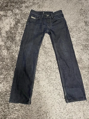 Diesel Larkee mörkblå jeans straight - Säljer ett par Diesel Larkee 1985 jeans i mörkblå tvätt med klassisk straight fit. Jeansen är vinted, men i riktigt bra skick. Storleken är W29 L32. Materialet är slitstarkt denim och midjan är normal. Perfekt för dig som gillar tidlös stil. 