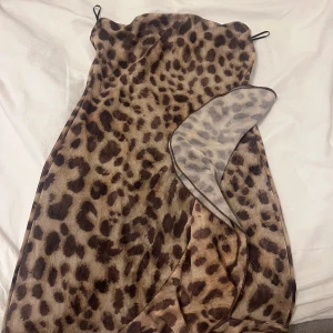 Leopardmönstrad kort klänning - Säljer en superfin kort klänning med leopardmönster och tunna axelband. Klänningen har volangdetalj framtill och sitter snyggt figurnära. Perfekt för dig som vill sticka ut och älskar djurmönster. Materialet känns lätt och luftigt.