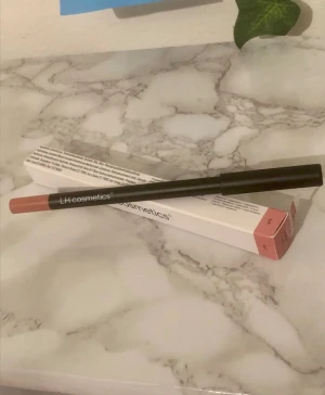 LH cosmetics läppenna i nude - Snygg läppenna från LH cosmetics i en nude-rosa ton. Pennan har en smal och stilren svart design med färgmarkering i ena änden. Perfekt för att definiera och forma läpparna med ett naturligt resultat.