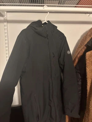 Svart vindjacka från Sail Racing - Svart vindjacka från Sail Racingmed huva och flera praktiska fickor med dragkedja. Jackan har en stilren look, lång ärm och diskret logotyp på ärmen. Perfekt för dig som gillar enkel och funktionell stil. VID SNABB AFFÄR 300!!