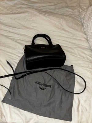 Zadig väska Sunny  - Zadig & Voltaire Sunny XS Bag Wings, knappt använd superfint skick! Dustbag och axelband följer självklart med.  Måtten på väskan är:  Bredd: ca 23 cm   Höjd: ca 14–14,5 cm   Djup: ca 11–11,5 cm   Kvitto finns digitalt🖤