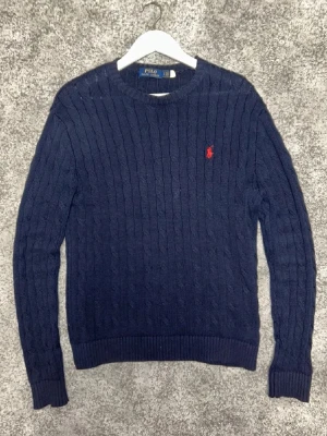 Mörkblå  stickad tröja Polo Ralph Lauren🙌🤩 - Snygg marinblå stickad tröja från Polo Ralph Lauren med klassiskt kabelstickat mönster och röd broderad logga på bröstet.  I storlek S🙌🤩
