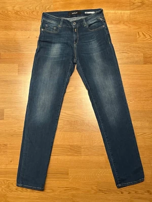 Replay jeans straight fit - Snygga blå jeans från Replay med klassisk femficksdesign och raka ben. Jeansen har subtila slitningar framtill och bak, samt Replay-läderpatch på bakfickan. Perfekt passform och stilren look som funkar till det mesta.