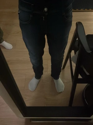 Mörkblå Replay jeans med smal passform - Säljer ett par mörkblå jeans från Replay med snygga slitningar och kontrastsömmar. Klassisk femficksmodell, smal passform och normal midja. Märkespatch bak och detaljerade bakfickor. Perfekta för dig som gillar stilrena och moderna jeans.