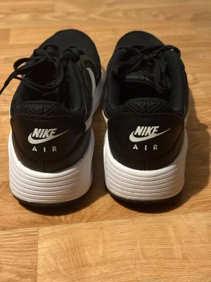 Svarta Nike Air sneakers med vit sula - Säljer ett par svarta Nike Air sneakers med vit sula och vit swoosh på sidan. Skorna har snörning och är tillverkade i en mix av skinn och mesh för en sportig look. Perfekta för dig som gillar klassisk streetstyle och vill ha bekväma skor till vardagen.