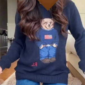 Mörkblå stickad tröja Polo Bear - Mörkblå stickad tröja från Polo Ralph L med ikoniska Polo Bear-motivet framtill. Tröjan har rund hals, ribbade muddar och RL-broderi nertill. Perfekt julklapp 