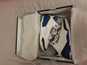 Nike Air Jordan 3 Retro blå/vit - Nike Air Jordan 3 Retro sneakers i vit och blå med svarta detaljer och klassiskt elephant print runt hälen och tån. Skorna har snörning, platt sula och rund tå. Tillverkade i skinn med inslag av syntetmaterial. Grym modell för dig som gillar streetwear och sneakers med attityd.