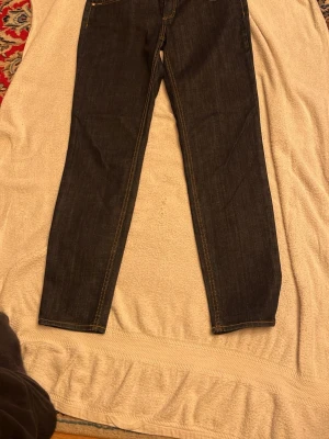 Mörkblå raka jeans från Hugo Boss - Snygga mörkblå jeans med raka ben och klassiska kontrastsömmar. Modellen har fem fickor och en enkel, stilren look som passar till sneakers eller boots. Jeansen är tillverkade i robust denim och har en tidlös vibe.