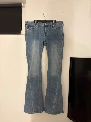 Bootcut jeans från True Religion - Snygga ljusblå bootcut jeans från True Religion med detaljer på bakfickorna. Jeansen har låg midja och ser ut som nya då jag använt dem ett fåtal gånger. Det är i storlek W30.                           Pris kan diskuteras!
