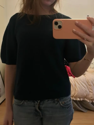 Mörkblå/grön stickad topp med kort ärm - En enkel och stilren mörkblå/grön stickad topp med rund halsringning och korta ärmar. Perfekt att matcha med jeans eller kjol för en avslappnad look. Mjuk och bekväm, passar till många tillfällen.