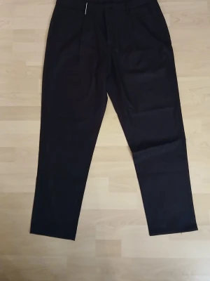 Svarta kostymbyxor från Temu storlek XL - Svarta kostymbyxor i klassisk rak modell med pressveck och diskreta bakfickor. Byxorna är tillverkade i 98% polyester och 2% elastan för en skön och följsam känsla. Perfekta för en clean och stilren look. Från Temu!