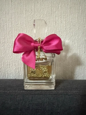 Juicy Couture parfym med rosett - Snygg parfymflaska från Juicy Couture med en stor rosa rosett och gulddetaljer. Perfekt för dig som vill ha en trendig accessoar på sminkbordet. Volym och ingredienser syns ej på bilderna.