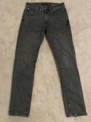 Grå jeans Superdry - Säljer ett par grå  jeans från Superdry. Jeansen har klassisk femficksdesign och svart patch bak i midjan.