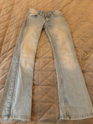 Bootcut jeans ljusblå H&M stl 152 - Ljusblå bootcut jeans från H&M i storlek 152. Snygg låg midja och justerbar midja för perfekt passform. Klassisk femficksmodell med coola bakfickor med lock och knapp. Materialet är 78% bomull, 20% polyester och 2% elastan.
