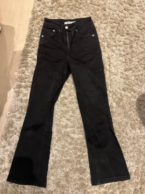 Svarta bootcut jeans från NA-KD - Säljer ett par svarta jeans från NA-KD i bootcut-modell. Byxorna har hög midja, klassiska fem fickor och dragkedja med knapp framtill. Materialet är jeans och passformen är normal med utsvängda ben. Perfekta för en trendig look.