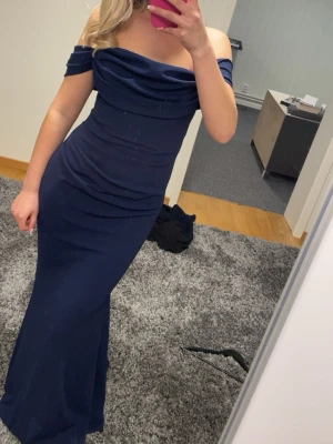 Marinblå balklänning från Goddiva - marinblå långklänning från Goddiva London. Klänningen har offshoulder-design med draperad överdel och figurnära modell.