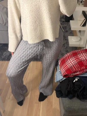 Grå ribbade stickade mjukisbyxor - Mysiga grå stickade mjukisbyxor med bred resår i midjan och snörning. Byxorna har ett ribbat kabelstickat mönster och raka, lite vidare ben. Aldrig använt 