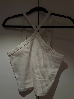 Vit ribbad croppad linnetopp - Säljer en vit ribbad linnetopp med korsade axelband framtill. 