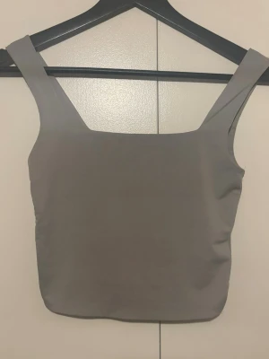 Grå croppad linnetopp - Säljer en enkel och stilren grå croppad linnetopp med breda axelband och rak halsringning. 
