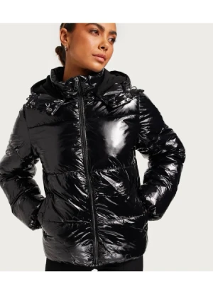 Svart glansig pufferjacka med huva - Säljer en svart glansig pufferjacka med huva och dragkedja framtill. Jackan har en quiltad look och är perfekt för kalla dagar. Den har en oversized känsla och är riktigt mjuk och skön att bära. Snygg och trendig stil som passar till många outfits.