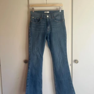 Blå bootcut jeans från Gina Tricot - Snygga blå jeans från Gina Tricot med bootcut passform och klassisk femficksdesign. Jeansen har medellåg midja och är tillverkade i ett mjukt denimtyg. Perfekta för dig som gillar en retroinspirerad look med utsvängda ben.