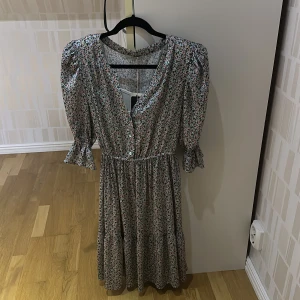 Blommig klänning 40 oanvänd - Supersöt långklänning från EKOL med småblommigt mönster i pastellfärger. Klänningen har v-ringning, knappar framtill, puffiga långärmar med vadd och volang vid ärmslut och markerad midja. Perfekt för dig som gillar romantisk och vintageinspirerad stil. Helt oanvänd i ganska fin material. Köpt utomland i en elegant butik:)