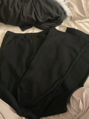 Svarta ribbade leggings - Säljer ett par svarta leggings med ribbad struktur. De är stretchiga och har en enkel, clean look utan synliga detaljer. Perfekta för chill dagar eller när du vill ha något bekvämt men ändå snyggt.
