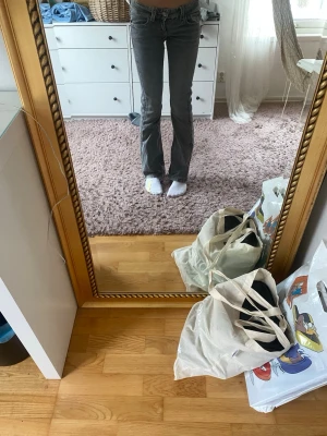 Grå bootcut jeans med låg midja - Säljer ett par gråa bootcut jeans med låg midja och klassisk femficksdesign. Jeansen har en snygg, lite utsvängd passform och är perfekta för dig som gillar en avslappnad men trendig stil.