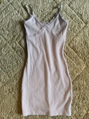 Ljuslila ribbat med spets - Sött ljuslila med tunna axelband och ribbad struktur. Dekorerat med spetsdetaljer vid bysten och v-ringning. Mjuk och stretchig känsla, perfekt för mysiga kvällar hemma.