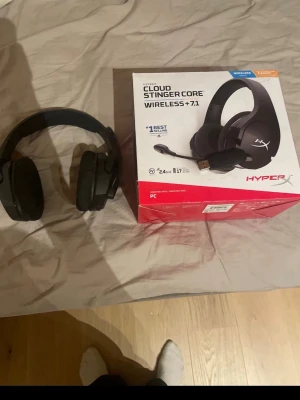 HyperX Cloud Stinger Core Wireless 7.1 - Säljer ett par svarta HyperX Cloud Stinger Core Wireless 7.1 gamingheadset. De är over-ear, har en stilren design med HyperX-logga på kåporna och är tillverkade i plast med mjuka öronkuddar. Perfekt för gaming med trådlös anslutning och surroundljud.