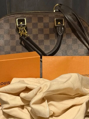 Äkta Louis Vuitton Alma Pm  - Säljer en äkta Louis Vuitton väska med inköpspris och värde direkt från butik för 20400kr. Allt är inkluderat i väskan förutom boxen men tygpåse finns med som skydd. Kvitto och äktehetsbevis följs med. Endast skada är ett litet slitage på bandet vid ett av hålen som knappt syns. Resten av väskan är så gott som ny. 