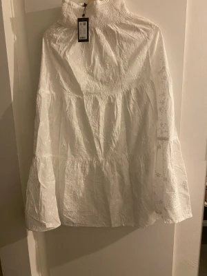 Vit kjol - Säljer en superfin vit kjol i storlek XS med broderade blommor och smock upptill. perfekt för sommarens alla tillfällen. Tillverkad i luftig bomull för en skön känsla. Prislapp kvar ✨