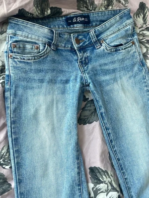 Ljusblå jeans från G. Rise - Snygga ljusblå jeans från G. Rise med klassisk femficksmodell och slitna detaljer. Jeansen har låg midja och utsvängda ben, perfekta för en avslappnad och trendig look. Tillverkade i mjuk bomullsdenim som är skön att bära hela dagen.