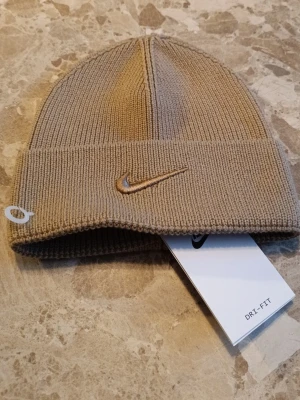 Mössa Nike oanvänd - Fin Nike mössa som original märket är Nike. Den är helt oanvänd med alla etiketter på. Alla qr koder elder till deras hemsida så att den är riktig. Mössa är fin och stretchig om tillåter dig att ha en stor komfort. Skriv till mig om det är frågor!