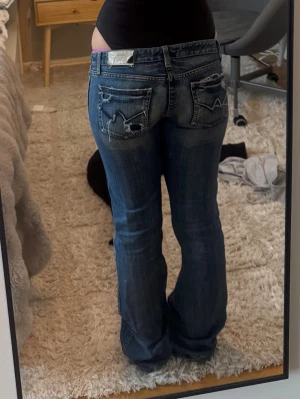 Levis 517 blå bootcut jeans - Säljer ett par klassiska Levis 517 jeans i blå tvätt med bootcut passform och låg midja. Jeansen har slitna detaljer på bakfickorna och är gjorda i tåligt denimtyg. Perfekta för dig som gillar en retro vibe och vill ha ett par riktigt snygga jeans. Sönder på baksidan vid bootcutten men inget man tänker på, rätt snyggt faktiskt. Säljer pågrund av att de blivit för tajta i midjan. Jag brukar ha 26 och de är ungefär i storlek 25, men de sitter jättefint förutom att ja inte kunde stänga de😅