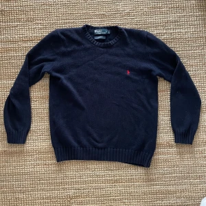 Ralph Lauren tröja - En riktigt snygg klassisk stickad Ralph lauren tröja i storlek S som kan vara riktig go till sommarkvällar eller när det blir lite kyligare i luften. Den enda defekten som finns är den lilla fläcken som syns om man kollar noggrant, men sitter på insidan av ärmen så den syns inte alls annars. Dessutom är det kanske noterbart att den har blivit tvättat några gånger men absolut inte överdrivet. Vid några funderingar är det bara att skriva! 