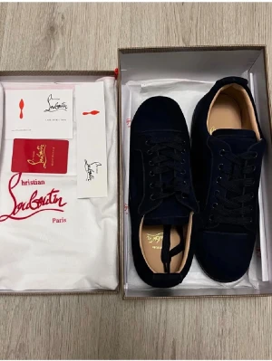 Mörkblå mocka sneakers Christian Louboutin - Snygga mörkblå sneakers från Christian Louboutin i mjuk mocka med klassisk rund tå och svarta snören. Skorna har en stilren design och diskreta detaljer, perfekt för dig som vill ha något exklusivt men ändå enkelt. Kommer med originalkartong och dustbag. Bara ställa frågor privat, svarar så snabbt som möjligt👍