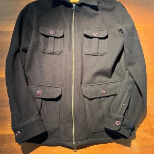 Mörk blå jacka från John Henric - Säljer en stilren mörkblå overshirt från John Henric i storlek M. Jackan har en dragkedja framtill och fyra fickor med knappar. Den är långärmad och perfekt för höst- och vårsäsongen. Materialet känns mjukt och av hög kvalitet.